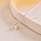 A miniature silver watering can jewellery charm on a silver rolo chain.